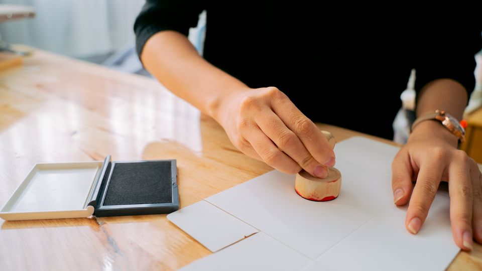 Mãos carimbando um documento sobre a mesa do cartório