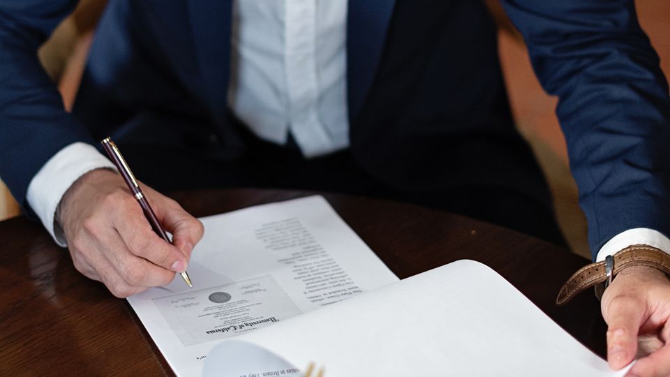 Pessoa assinando documentos em uma mesa de escritório