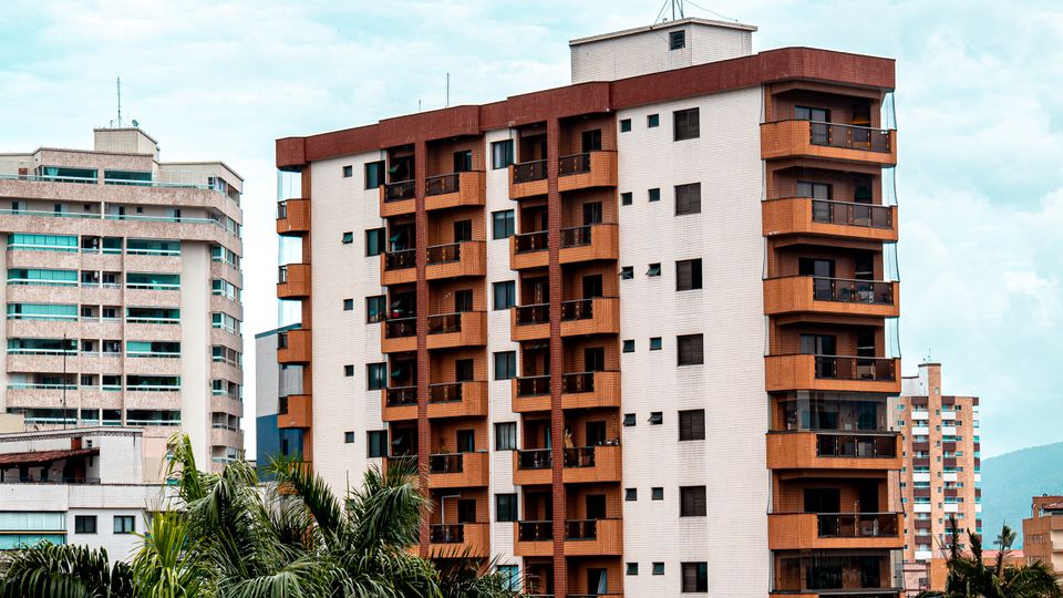 Prédio residencial brasileiro visto da rua, com palmeiras ao redor